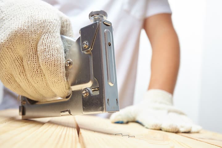 Male installer using stapler for wooden plank