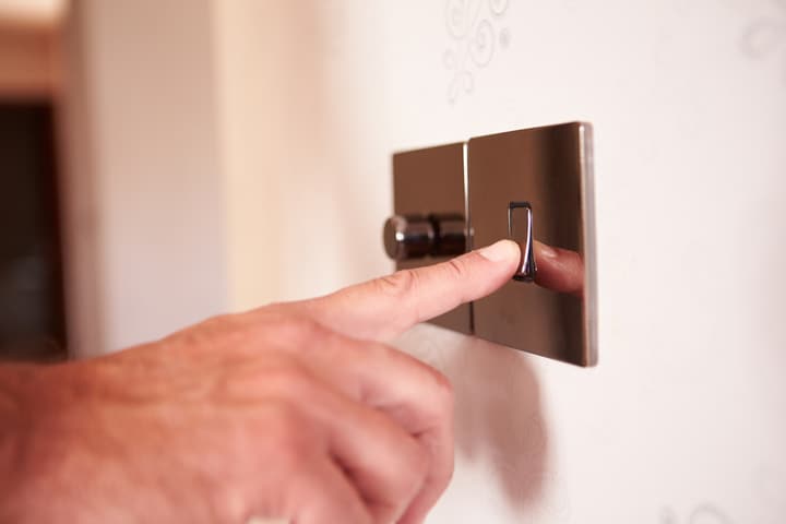 Close Up Of Man Turning On Electric Light Switch