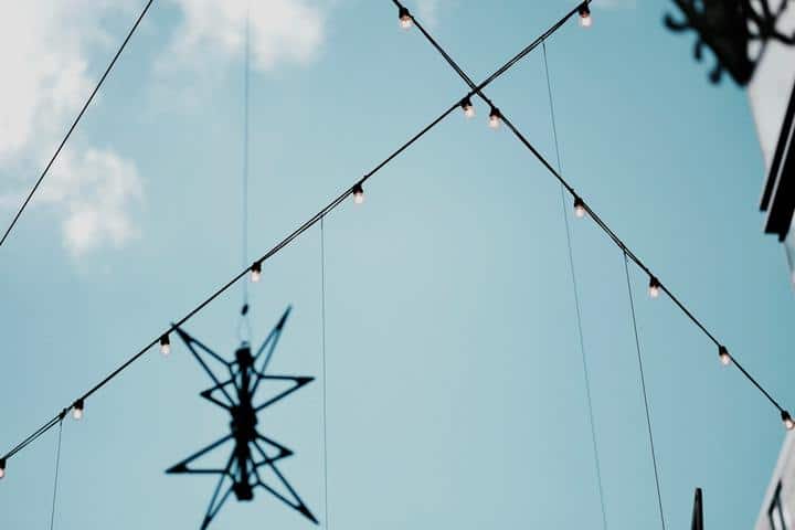 two wires of light bulbs hanging in the air with sky view