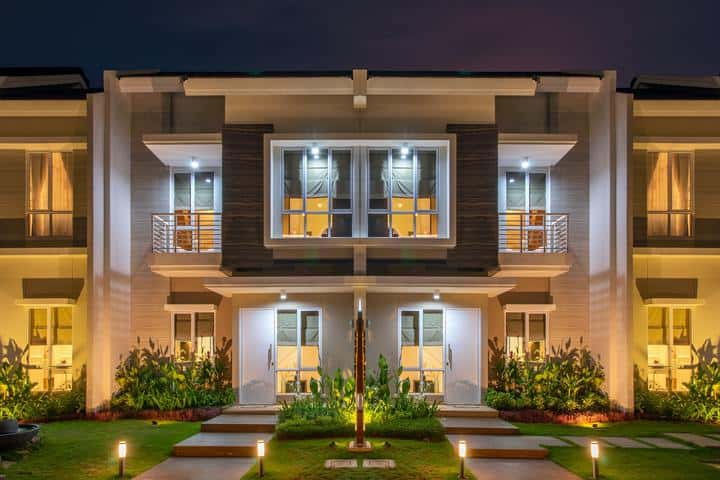 A large white villa at night with eight windows and two lighted pathways.