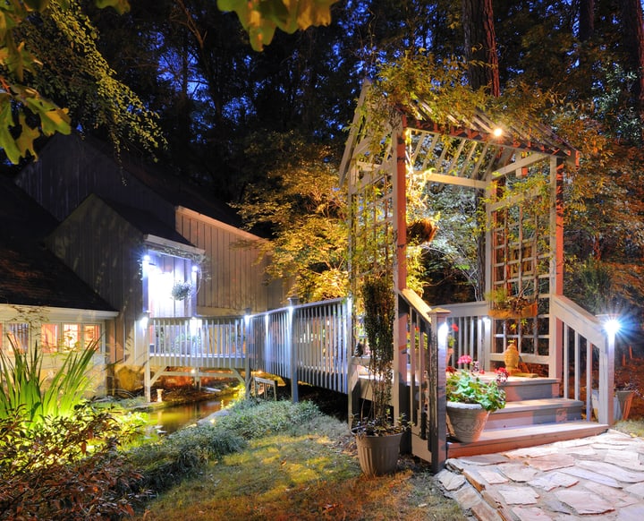 House exterior with porch walkay over a pond and lighting