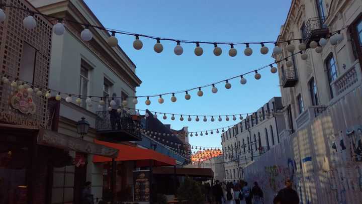 Densed bulbs of string patio lights hanging above the cozy street in Tbilisi