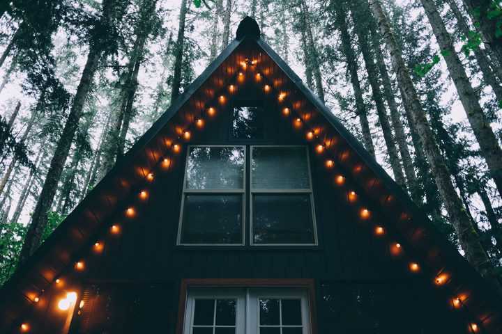 A house in woods with hanging patio lights at its front size
