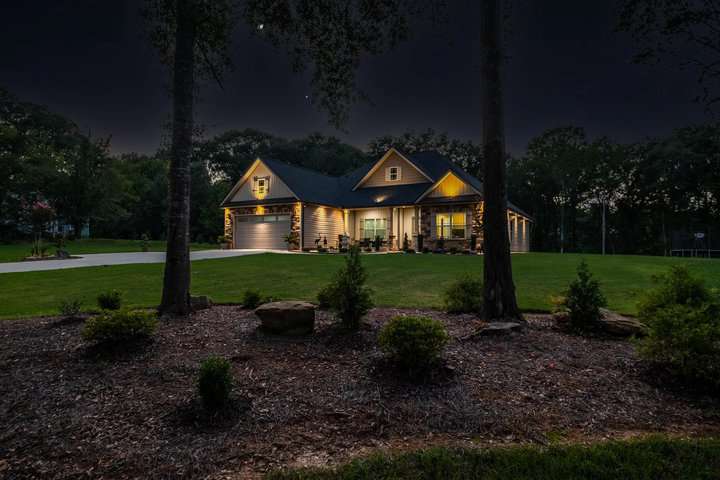 lighted family house at night with garden and woods around