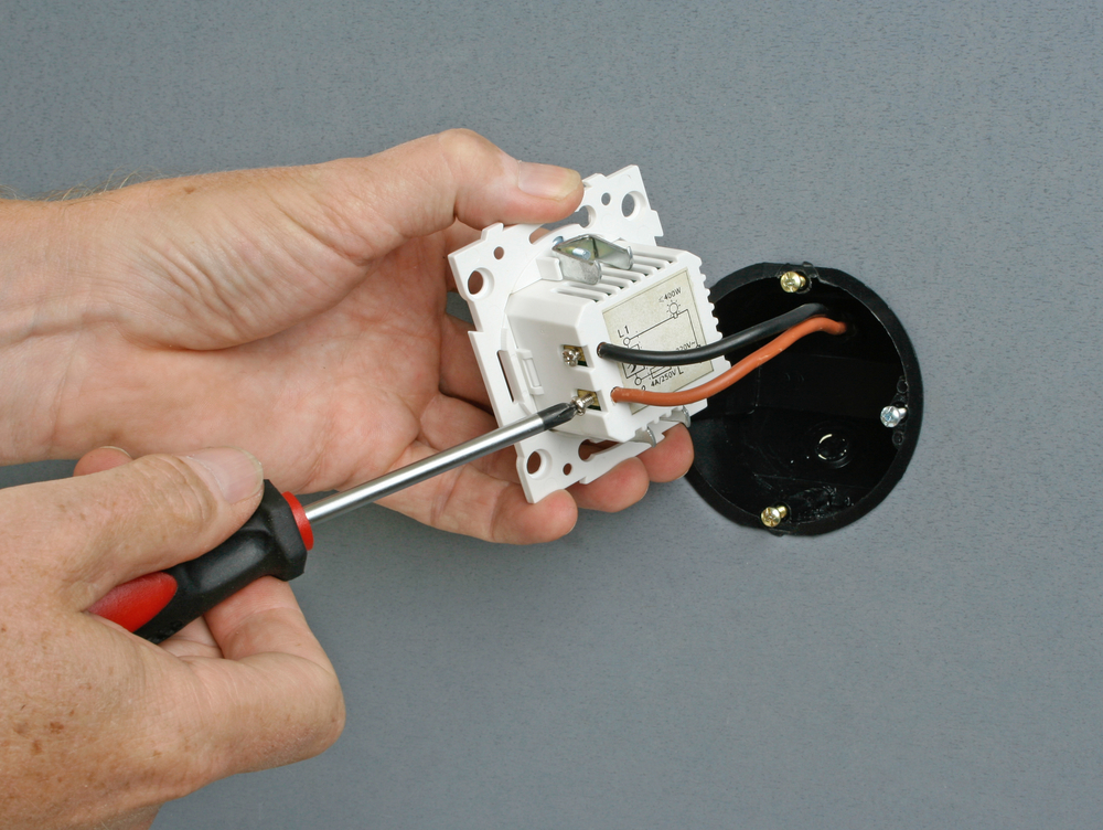Electrician installing a dimmer switch in a wall socket