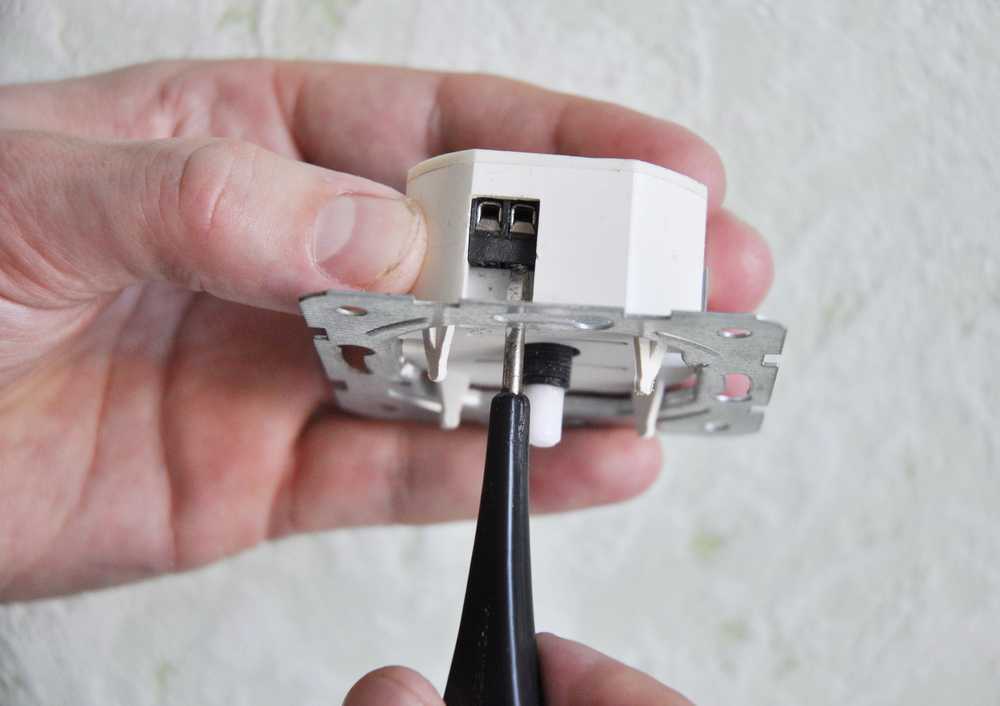 Electrician repair a dimmer switch in a wall socket