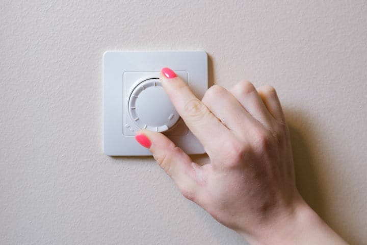 Woman's hand adjusts the lighting with a dimmer lever