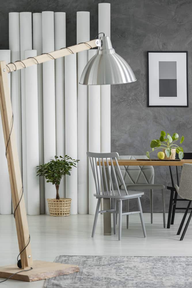  Wooden oversize lamp standing in the bright dining room with wire wrapped around the leg