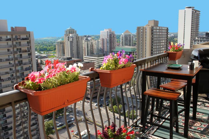 Rooftop patio with table and stool chairs and flowers on the railing