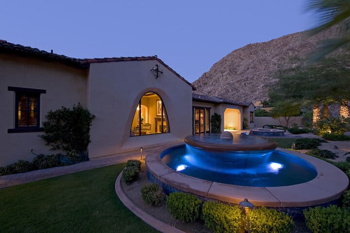 House exterior with fountain in garden at dusk