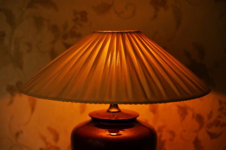 Pleating lampshade with warm light in dark room, closeup